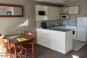 a kitchen with a counter and a table and a kitchen with white appliances at Opuke Crash Pad Methven - with mountain views. in Methven
