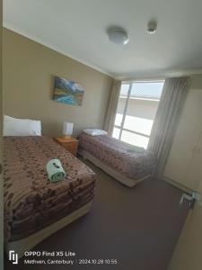 a bedroom with two beds and a large window at Opuke Crash Pad Methven - with mountain views. in Methven