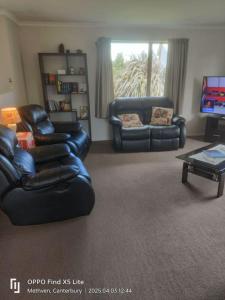 a living room with two leather couches and a tv at Methven Crash Pad in Methven