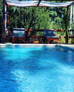 a swimming pool with two chairs and a gazebo at Casa Boutique de la Sierra in Sierra de los Padres