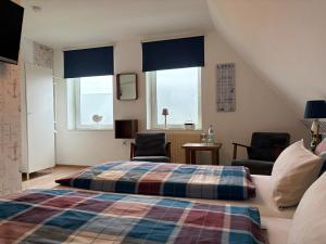 a bedroom with a bed and two chairs and windows at Pension Blaue Nordseewelle in Neuharlingersiel