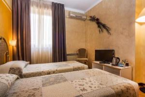 a hotel room with two beds and a television at Hotel Le Pageot in Aosta