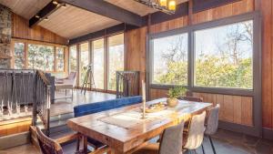 a dining room with a wooden table and some windows at Asher by AvantStay in Asheville