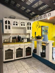 a kitchen with white cabinets and a yellow wall at Hermosa Casa Familiar en Suchitoto in Aguacayo