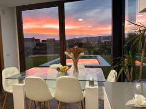 a dining room with a glass table and white chairs at CESANTES VILLAGE e in Pontevedra +28 photos