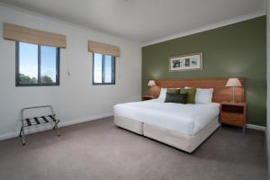 a bedroom with a large white bed and two windows at Leisure Inn Spires in Leura