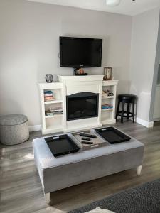 a living room with a white entertainment center with a tv at Lake Simcoe Beach Oasis with Backyard and Firepit in Georgina +15 photos