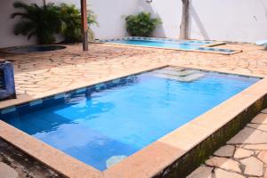 a swimming pool with blue water on a stone patio at Hotel Imperador Caldas Novas - GO - Facil acesso aos parques aquaticos e polo gastronômico noturno in Caldas Novas