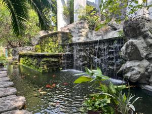 a koi pond in a garden with a waterfall at NexStay Bangkok Appartment in Bangkok