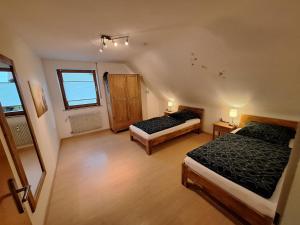 an attic room with two beds and a window at Gemütliches Ferienhaus in Schnaid mit zwei separaten und geräumigen Wohnungen - ausgestattet mit je einer großen Küche, zwei Schlafzimmern und einem Badezimmer in Hallerndorf