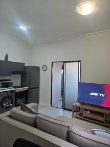 a living room with a couch and a flat screen tv at Sir Chase Place in Boksburg