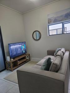 a living room with a couch and a flat screen tv at Sir Chase Place in Boksburg