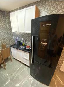 a kitchen with a black refrigerator and a counter at Seu Refúgio no Guarujá in Guarujá