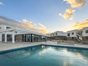 a house with a swimming pool in front of a building at Kantara Beach Resort Apartment FeMa in Athalassa