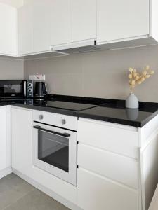 a kitchen with white cabinets and a black counter top at Kantara Beach Resort Apartment FeMa in Athalassa