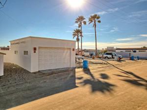 a building on the beach with palm trees in the background at Beautiful Beachfront Condo Olas I 16 in Puerto Peñasco