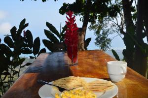 a table with a plate of eggs and chips and a cat at Hostal Mirador Mar Nevado in Buritaca