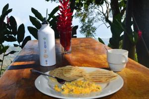 a plate of eggs and chips on a table with a drink at Hostal Mirador Mar Nevado in Buritaca +26 photos