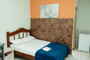 a small bedroom with a bed and a tile wall at Lagos Hotel in Itajubá