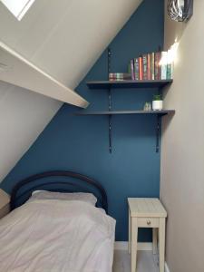a bedroom with a blue wall with a bed and shelves at Het Gewei in Burgh Haamstede