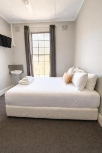 a large white bed in a room with a window at Federal Hotel Mudgee in Mudgee