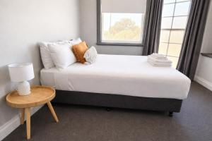 a bedroom with a bed with a table and a window at Federal Hotel Mudgee in Mudgee +6 photos