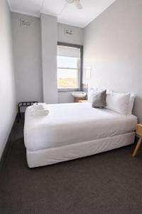 a large white bed in a room with a window at Federal Hotel Mudgee in Mudgee