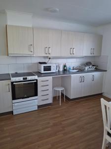 a kitchen with white cabinets and white appliances at bekväm villa in Fliseryd