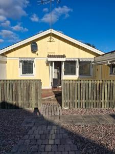 a yellow house with a wooden fence at bekväm villa in Fliseryd
