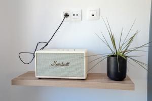a small radio sitting on a wooden shelf with a plant at East Coast in Alyki