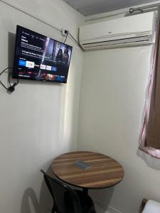a room with a table and a tv on the wall at Hotel Globo in Goiânia