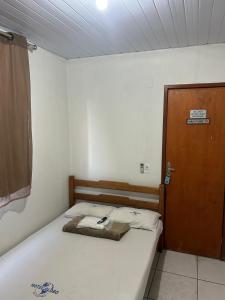 a small bedroom with a bed and a wooden door at Hotel Globo in Goiânia