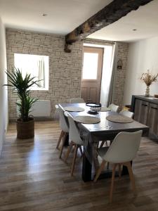 a dining room with a table and white chairs at Locéane in Le Pêchereau