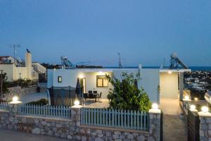 a small white house with a fence and lights at Sebastian Villas in Afantou