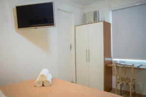 a room with a table with a tv and a cabinet at Hermoso Apartamento, Centro de Búzios-5Min da Orla in Búzios