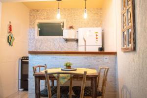 a kitchen with a table with chairs and a refrigerator at Hermoso Apartamento, Centro de Búzios-5Min da Orla in Búzios