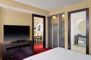 a bedroom with a flat screen tv and a living room at Park Plaza Leeds in Leeds