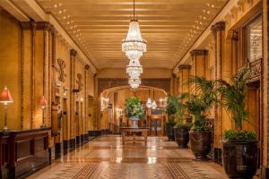 a hallway of a building with plants and a chandelier at The Roosevelt Hotel New Orleans - Waldorf Astoria Hotels & Resorts in New Orleans