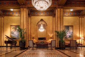 a lobby with a table and chairs and a chandelier at The Roosevelt Hotel New Orleans - Waldorf Astoria Hotels & Resorts in New Orleans
