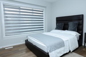 a bedroom with a bed and a large window at Kris Comfort Garden Suite in Edmonton
