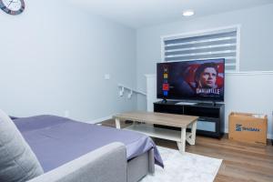 a living room with a bed and a flat screen tv at Kris Comfort Garden Suite in Edmonton