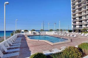 a swimming pool next to a building and the ocean at Charming condo with shared pool Gym and Tennis in Destin