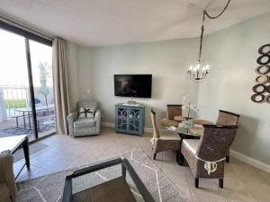 a living room with a table and chairs and a tv at Charming condo with shared pool Gym and Tennis in Destin