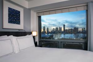 a bedroom with a large window with a city view at Conrad New York Downtown in New York +86 photos