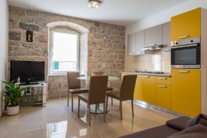 a kitchen with yellow cabinets and a table and chairs at Mila Apartment in Sinj