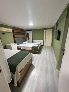 two beds in a room with green walls and wooden floors at Başkent Otel in Mudanya