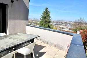 a balcony with a table and chairs and a view at Villa avec vue - terrasse - parking in Irigny
