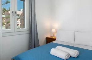 a bedroom with a blue bed with two towels on it at Sunset Realty in Ano Syros