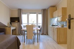 a room with a table and chairs and a kitchen at LC pokoje & apartamenty in Pobierowo