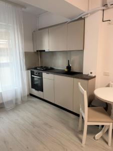 a kitchen with white cabinets and a table with a chair at The Urban Hide by D'or Selection in Bucharest